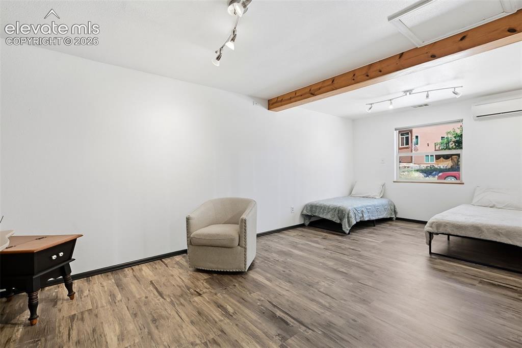Image 23 of 50: Spacious room featuring wood-finish flooring, exposed ceiling beam, recesse