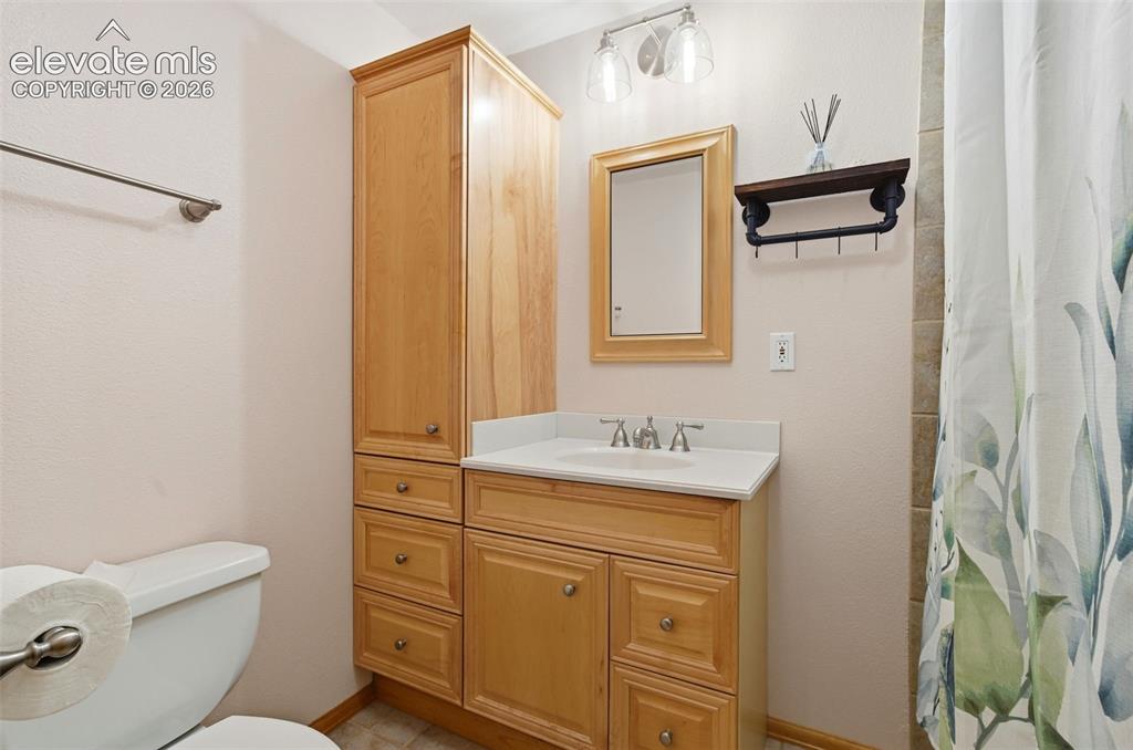 Image 25 of 50: Bathroom vanity featuring a light wood-finish cabinet with a white countert