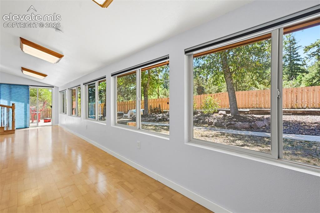 Image 26 of 50: A spacious room featuring wood-finish flooring, a series of large windows,