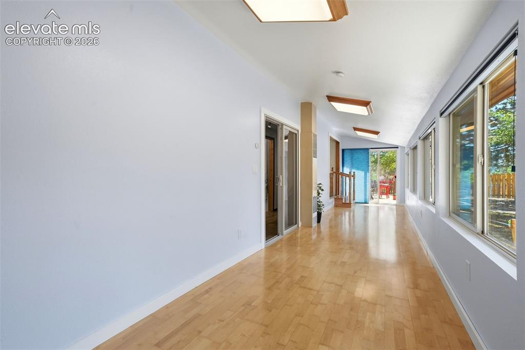 Image 27 of 50: Hardwood flooring extending through a brightly lit hallway