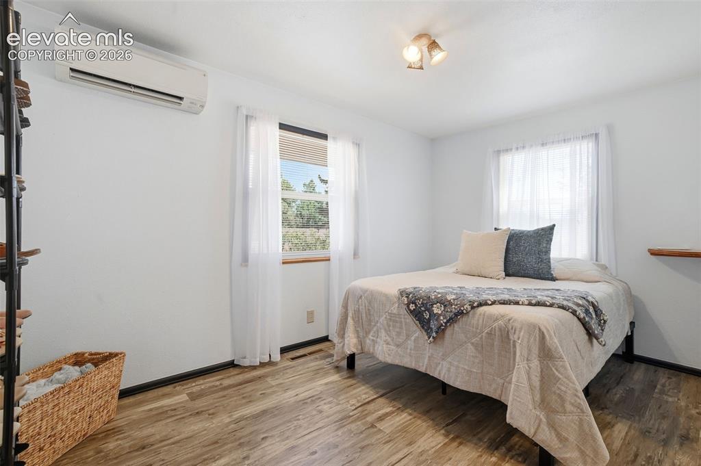 Image 28 of 50: Bright room featuring wood-finish flooring, white walls, and two large wind