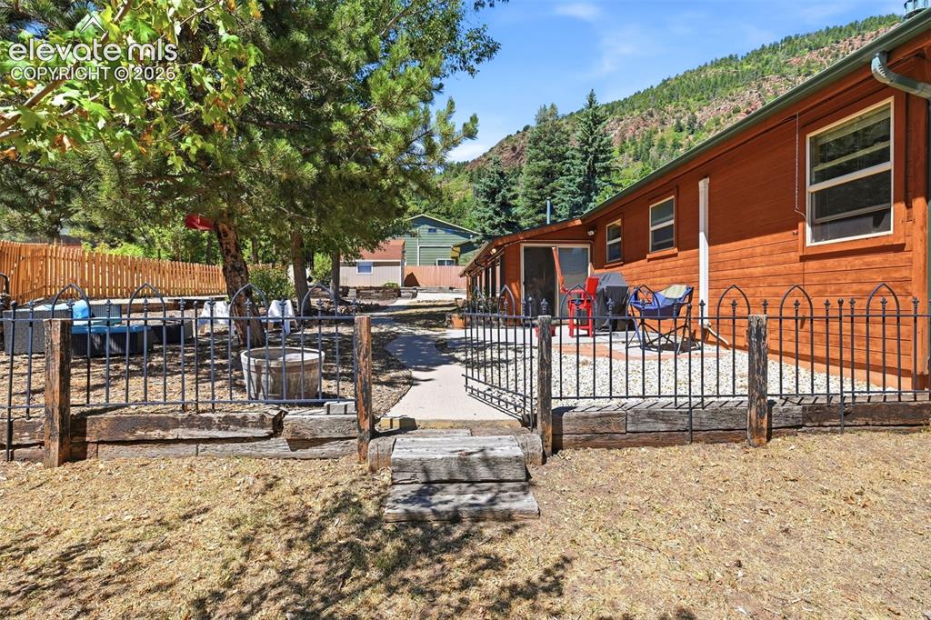 Image 37 of 50: Terraced backyard featuring a wooden-sided exterior, black metal fencing, g