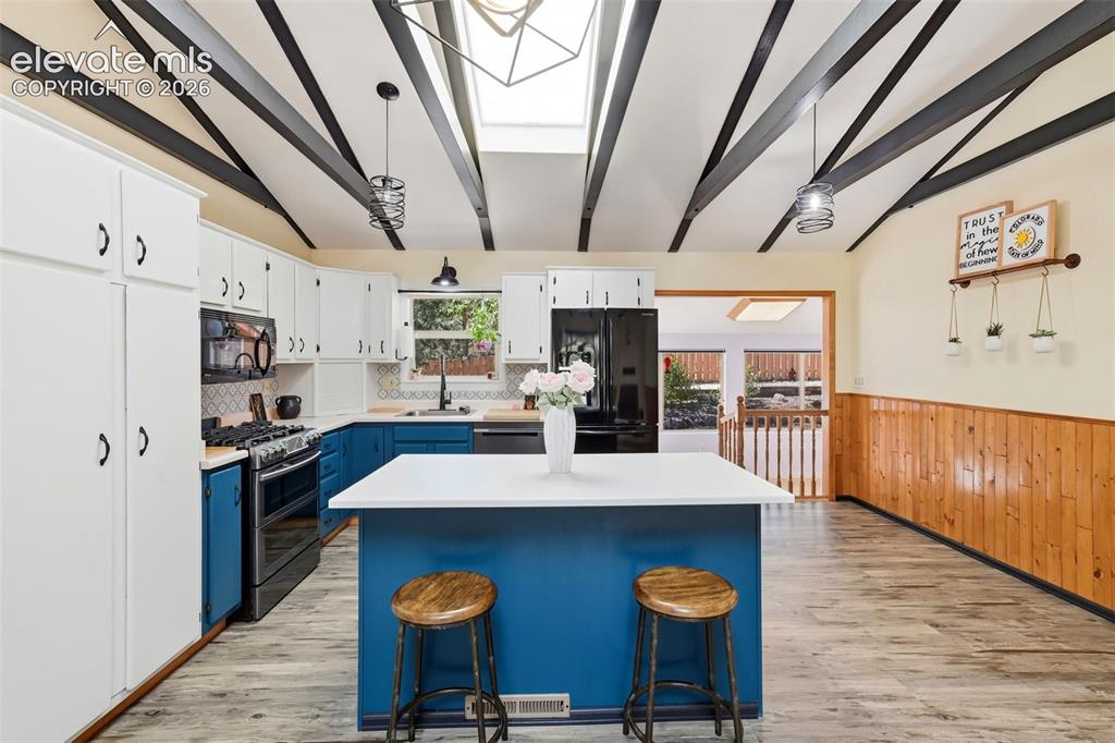 Image 4 of 50: Kitchen featuring a central island with a white countertop, two-tone cabine