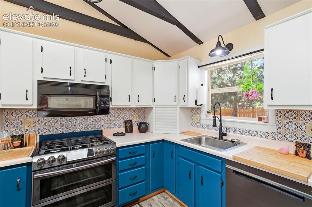 Image 7 of 50: Kitchen featuring painted cabinetry, patterned tile backsplash, stainless s