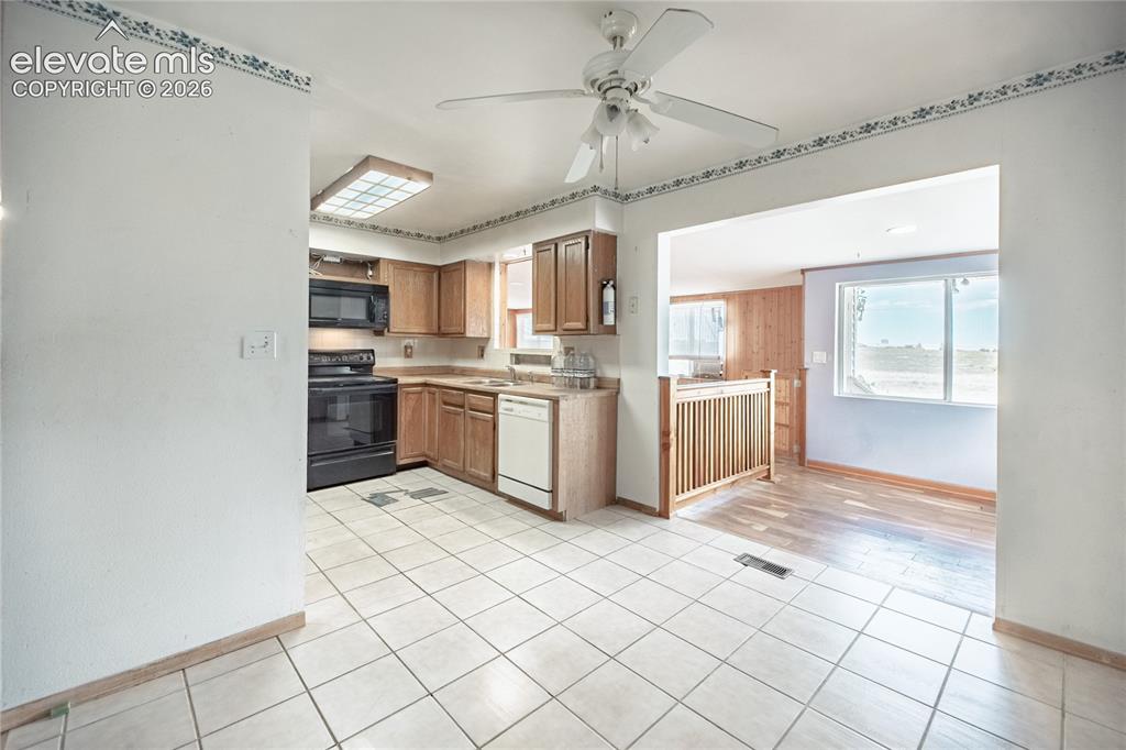 Image 11 of 50: Kitchen featuring wood cabinetry, black appliances, a ceiling fan, and tile