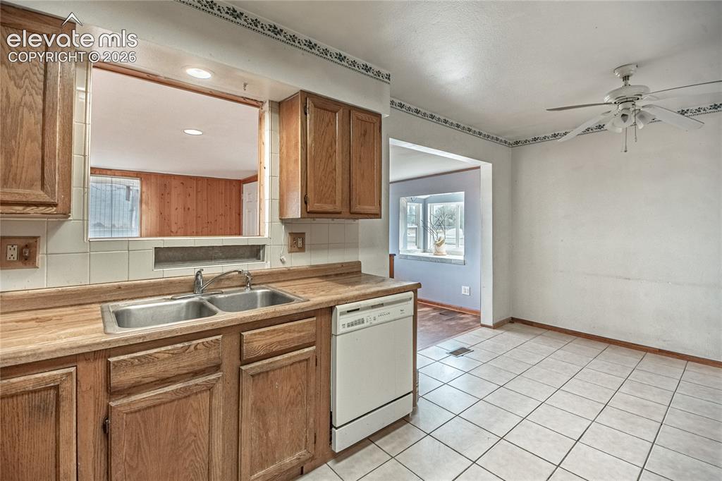 Image 14 of 50: Wood-finish cabinetry with a double basin stainless steel sink, tile backsp