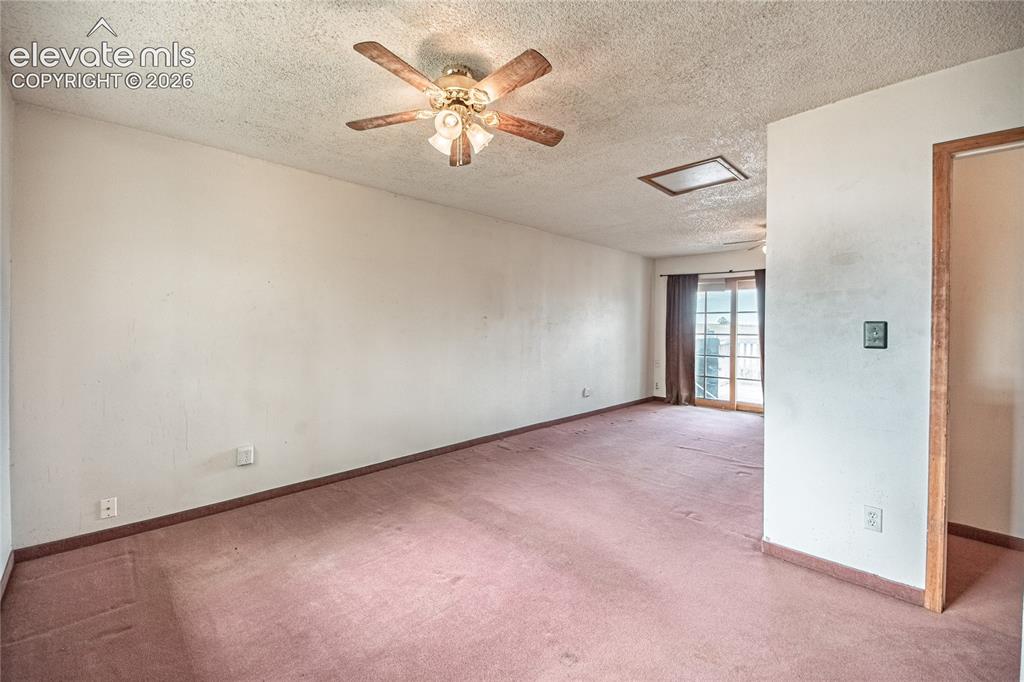 Image 22 of 50: Expansive room with neutral wall tones, textured ceiling, and a ceiling fan