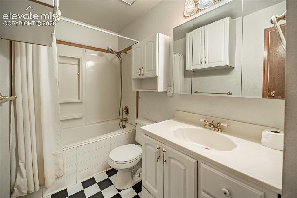Image 26 of 50: Bathroom featuring a white vanity with integrated sink, white cabinetry, a