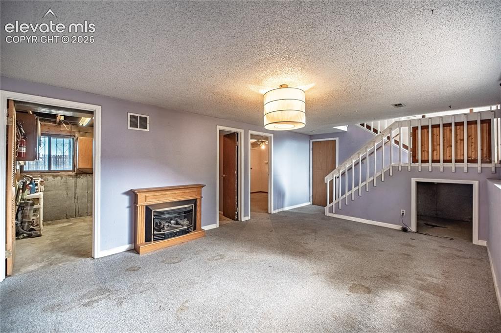 Image 32 of 50: Carpeted living area featuring a built-in fireplace with a wood-finish mant