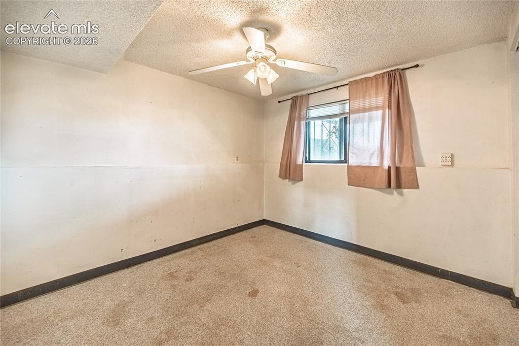 Image 34 of 50: Carpeted flooring with a ceiling fan light fixture and a window with securi