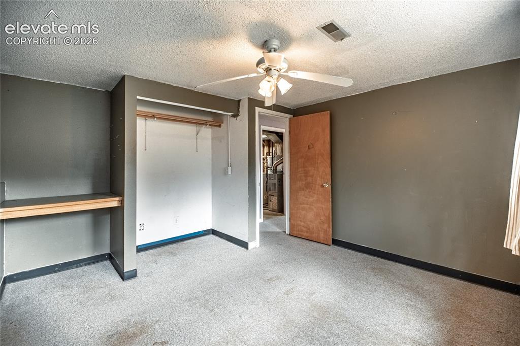 Image 38 of 50: Wall-to-wall carpeting, built-in shelving, and a ceiling fan with integrate