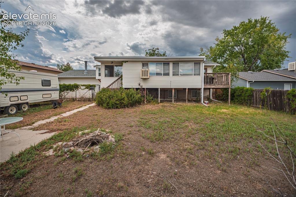 Image 46 of 50: Rear exterior with an elevated deck, lower-level patio, and a fire pit