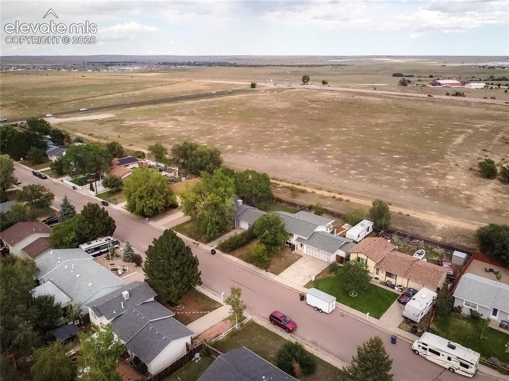 Image 48 of 50: Residential street with mature trees and a distant open landscape