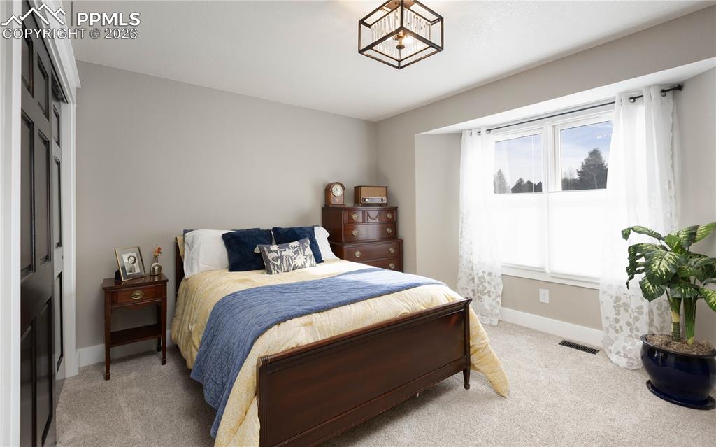 Image 18 of 42: Main-level bedroom with windows to the front of the home