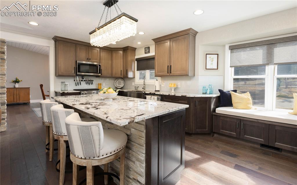 Image 5 of 42: Beautiful light fixtures, island and window seat in kitchen