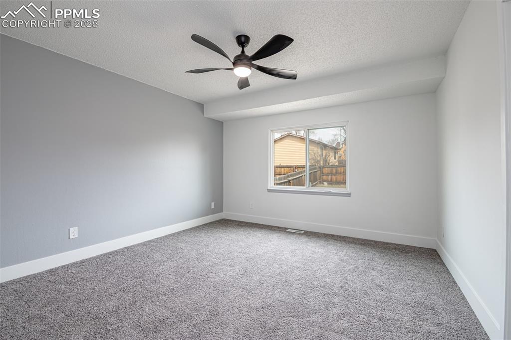 Image 13 of 33: Carpeted empty room with baseboards, a textured ceiling, and a ceiling fan