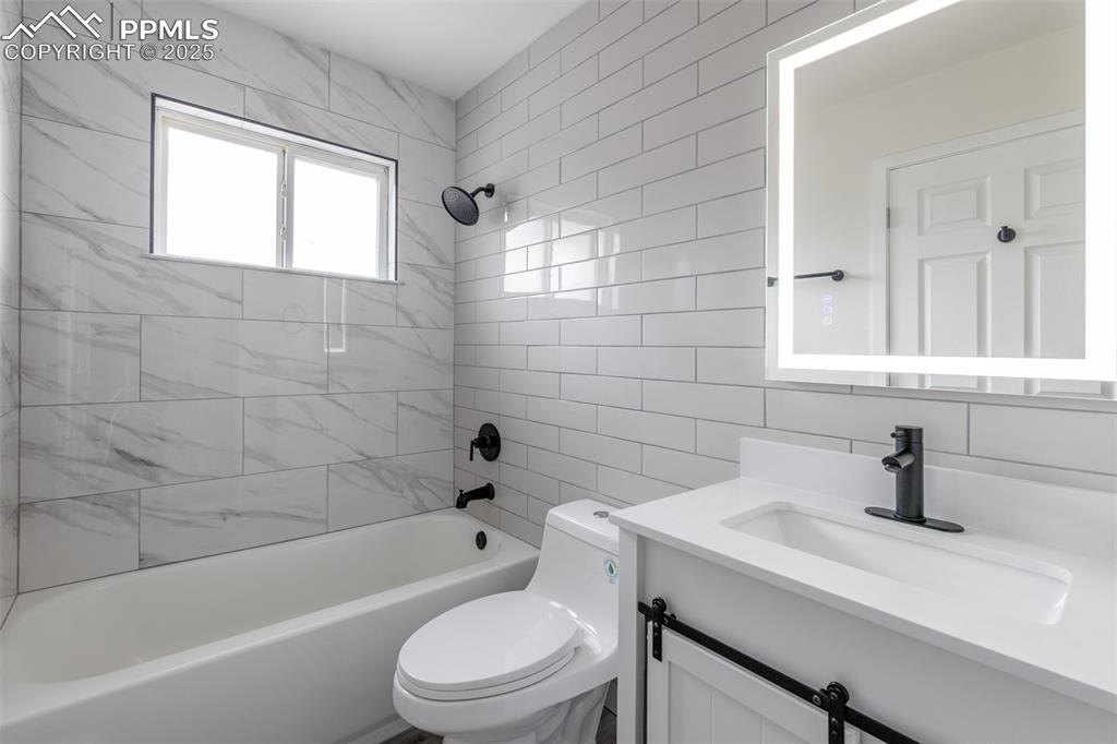 Image 15 of 33: Bathroom featuring toilet, backsplash, vanity, bathing tub / shower combina