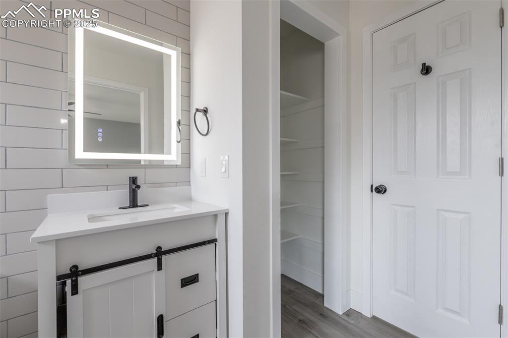 Image 16 of 33: Bathroom featuring wood finished floors, backsplash, and vanity