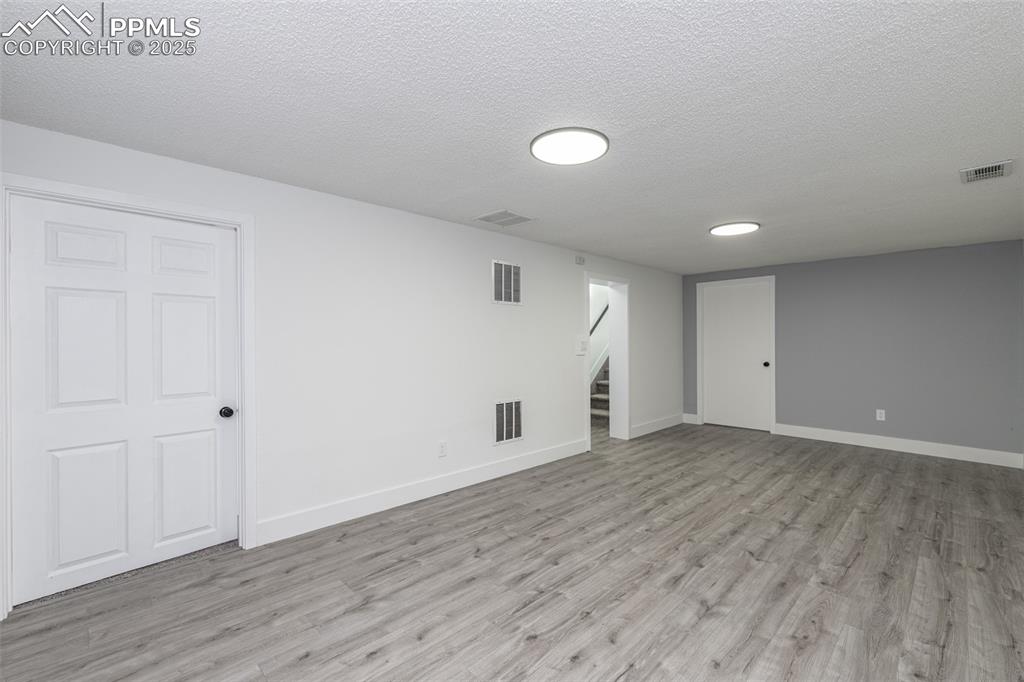 Image 20 of 33: Finished below grade area featuring visible vents, stairway, and light wood