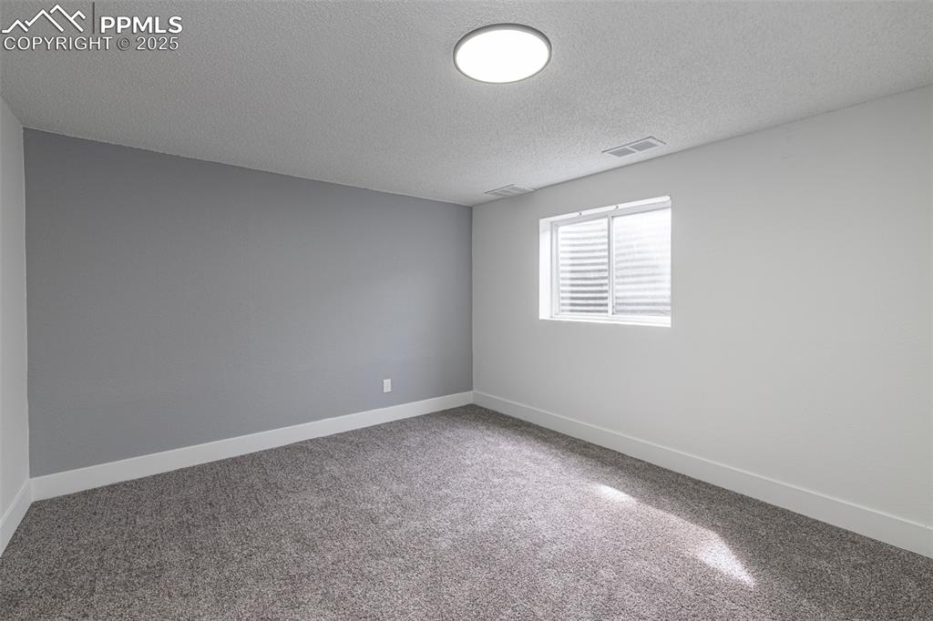 Image 21 of 33: Carpeted spare room featuring baseboards, a textured ceiling, and visible v