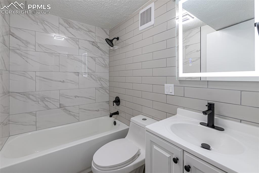 Image 22 of 33: Bathroom with toilet, a textured ceiling, shower / washtub combination, and