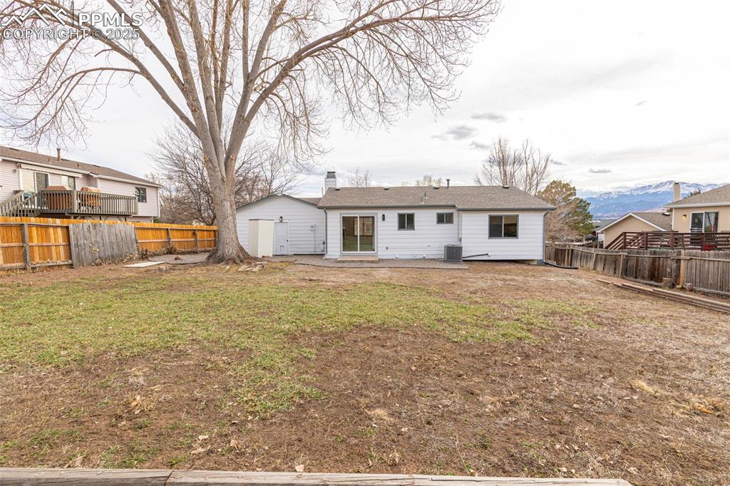 Image 29 of 33: Back of house featuring a fenced backyard, a lawn, central air condition un