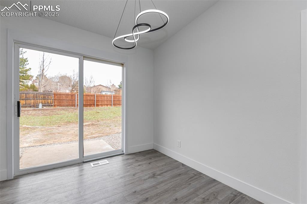 Image 9 of 33: Unfurnished dining area featuring wood finished floors, lofted ceiling, bas