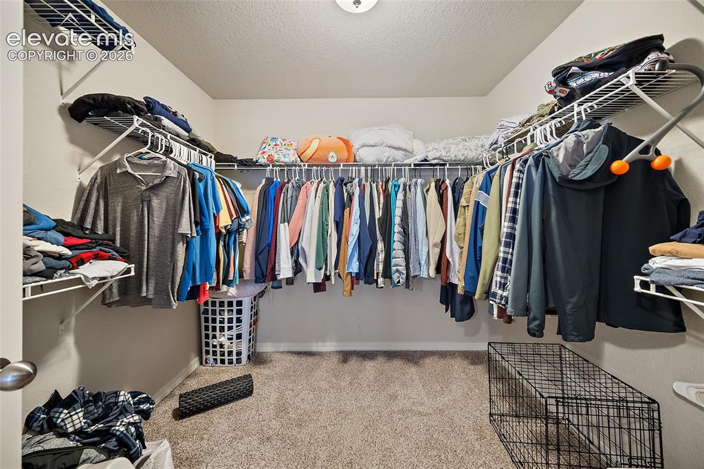 Image 26 of 49: Walk-in closet featuring wire shelving and hanging rods on three walls, pro