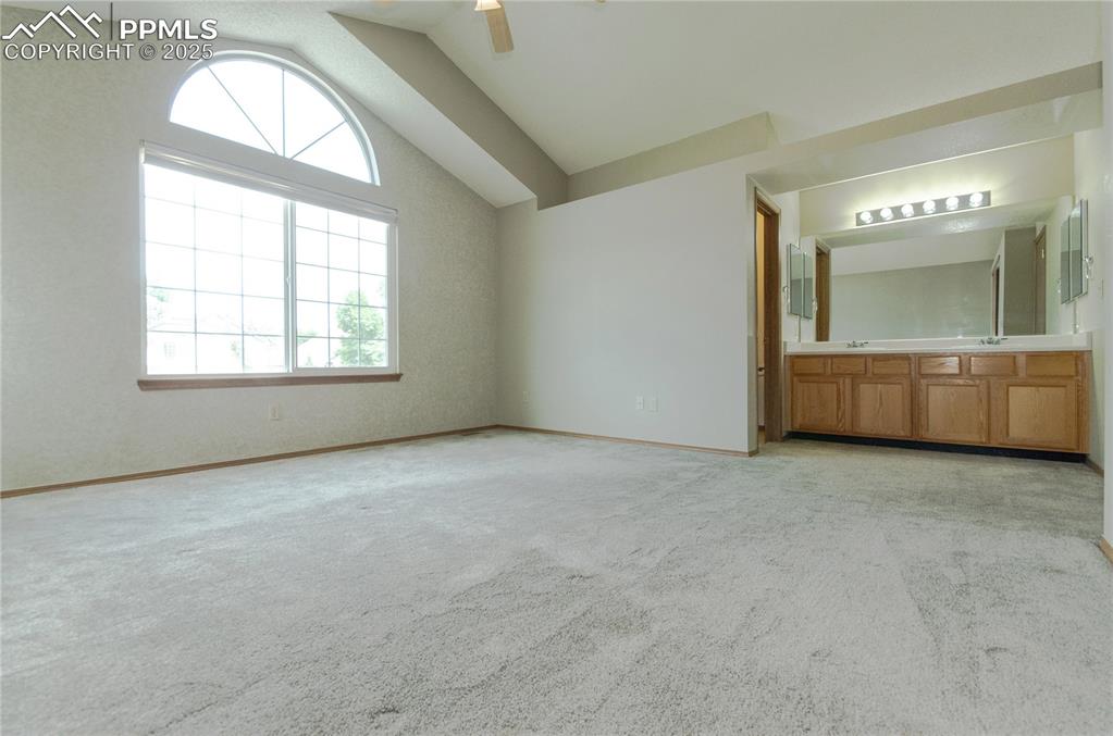 Image 15 of 41: Primary bedroom with vaulted ceilings. In the back ground is a double vanit