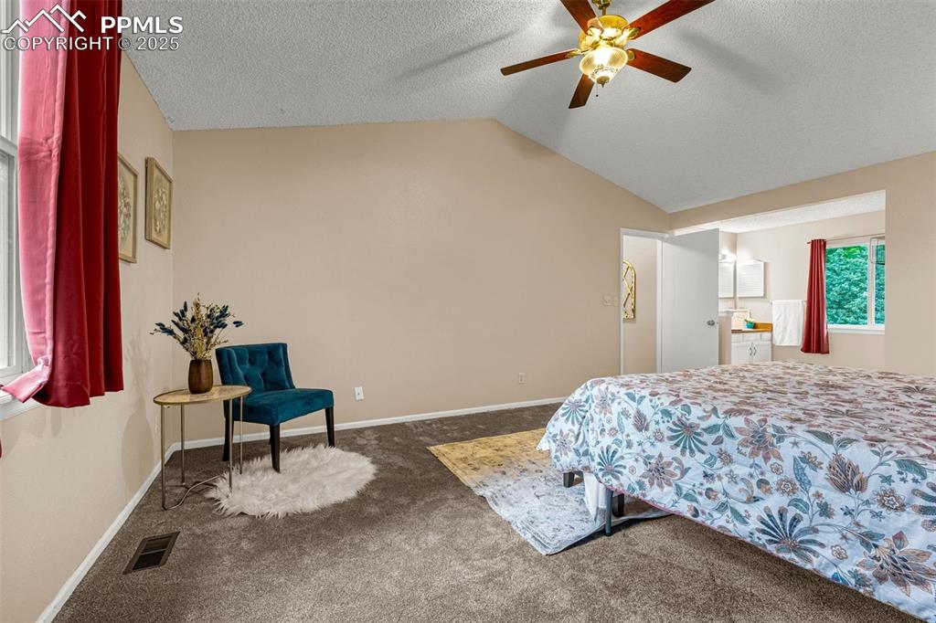 Image 15 of 40: Carpeted bedroom with vaulted ceiling, a textured ceiling, baseboards, and 