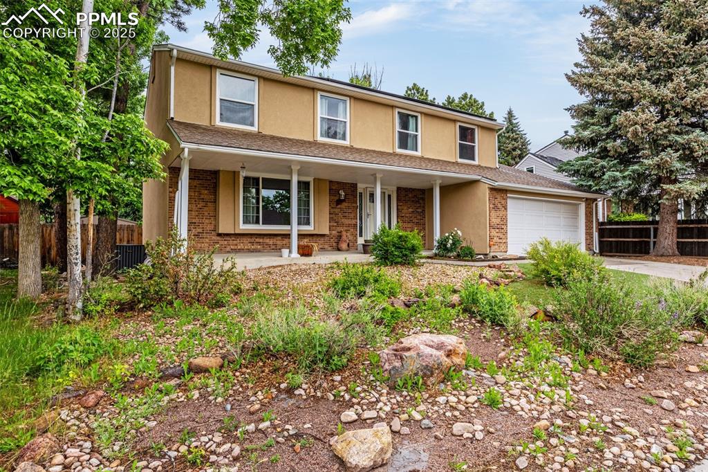 Image 2 of 40: Traditional-style house featuring stucco siding, a porch, an attached garag