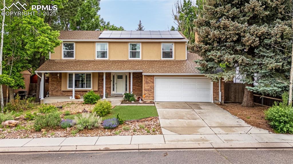 Image 33 of 40: Traditional home featuring covered porch, driveway, solar panels, stucco si