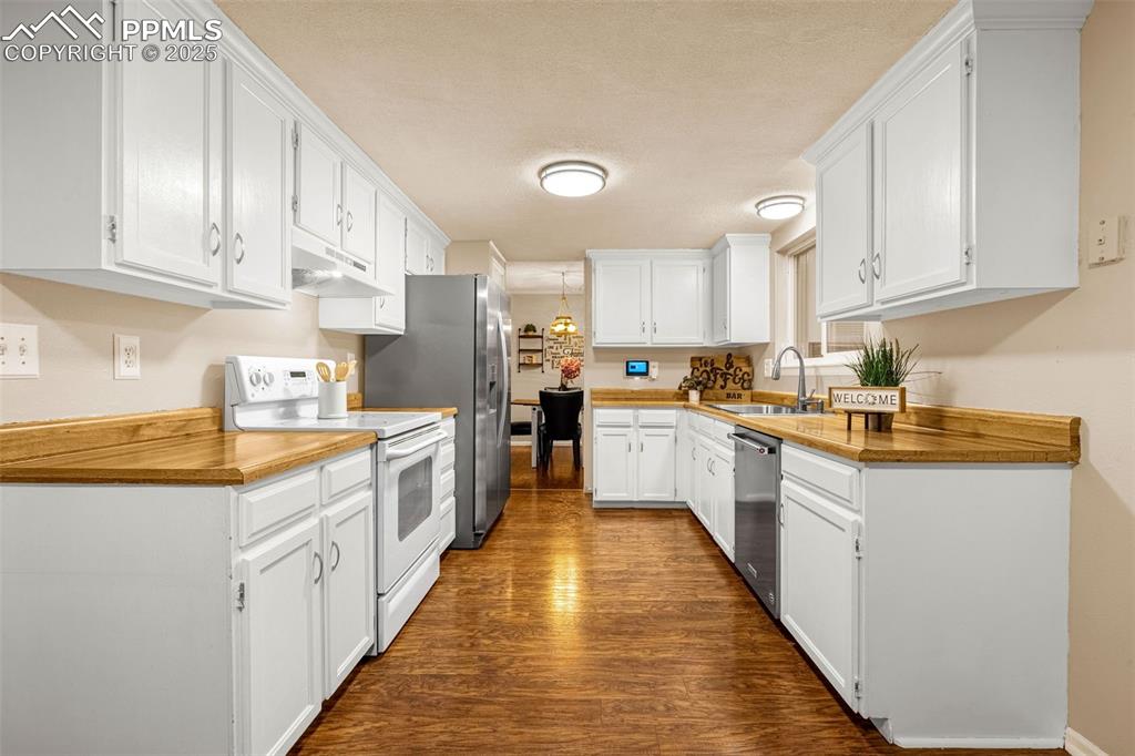Image 6 of 40: Kitchen featuring stainless steel appliances, a sink, under cabinet range h