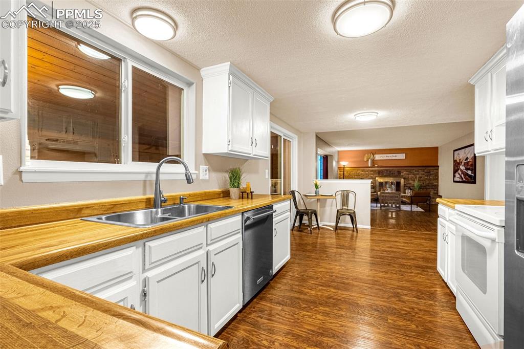 Image 7 of 40: Kitchen featuring stainless steel dishwasher, a sink, white range, white ca