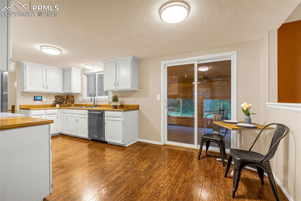 Image 9 of 40: Kitchen featuring stainless steel dishwasher, wooden counters, dark wood-ty
