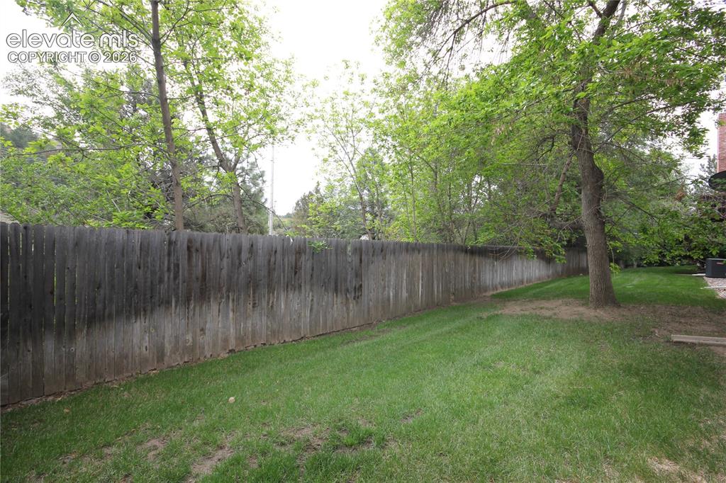 Image 28 of 33: Maintained yard in the back of the home with mature trees
