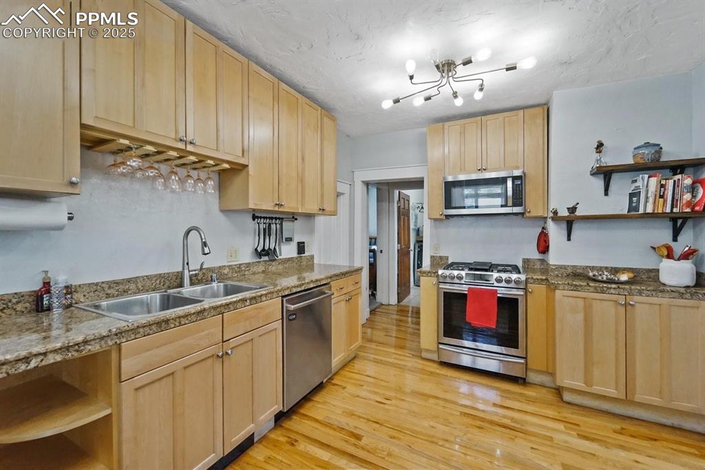 Image 10 of 28: Kitchen with open shelves, light brown cabinets, appliances with stainless 