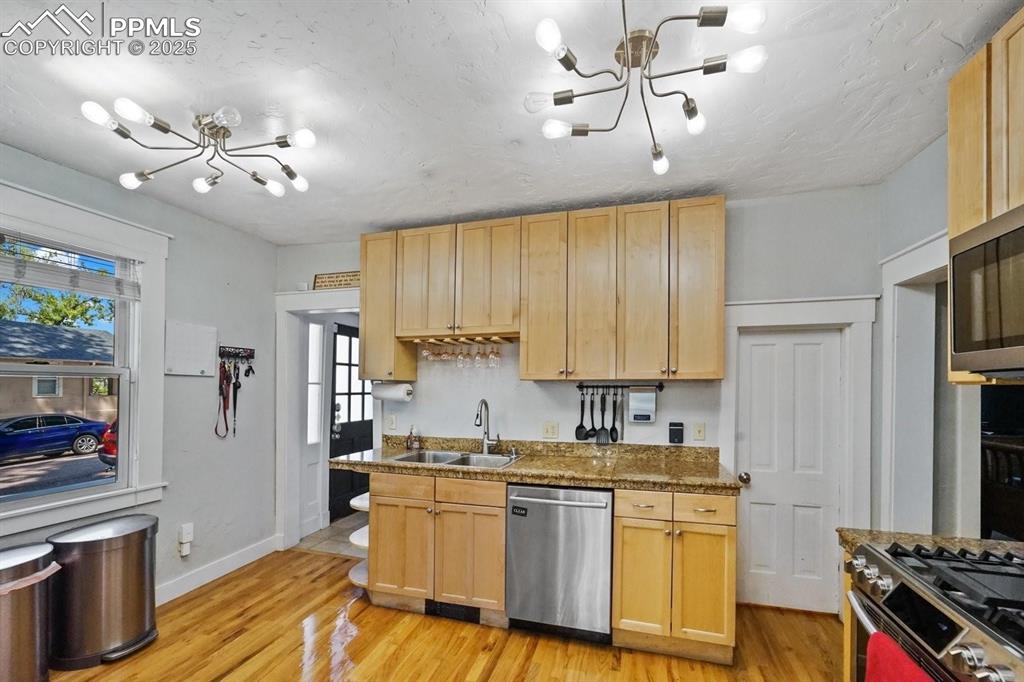 Image 11 of 28: Kitchen featuring a chandelier, stainless steel appliances, and light wood-