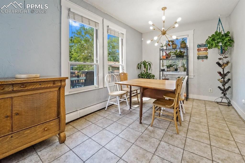 Image 12 of 28: Dining space featuring light tile patterned floors, a chandelier, and a bas