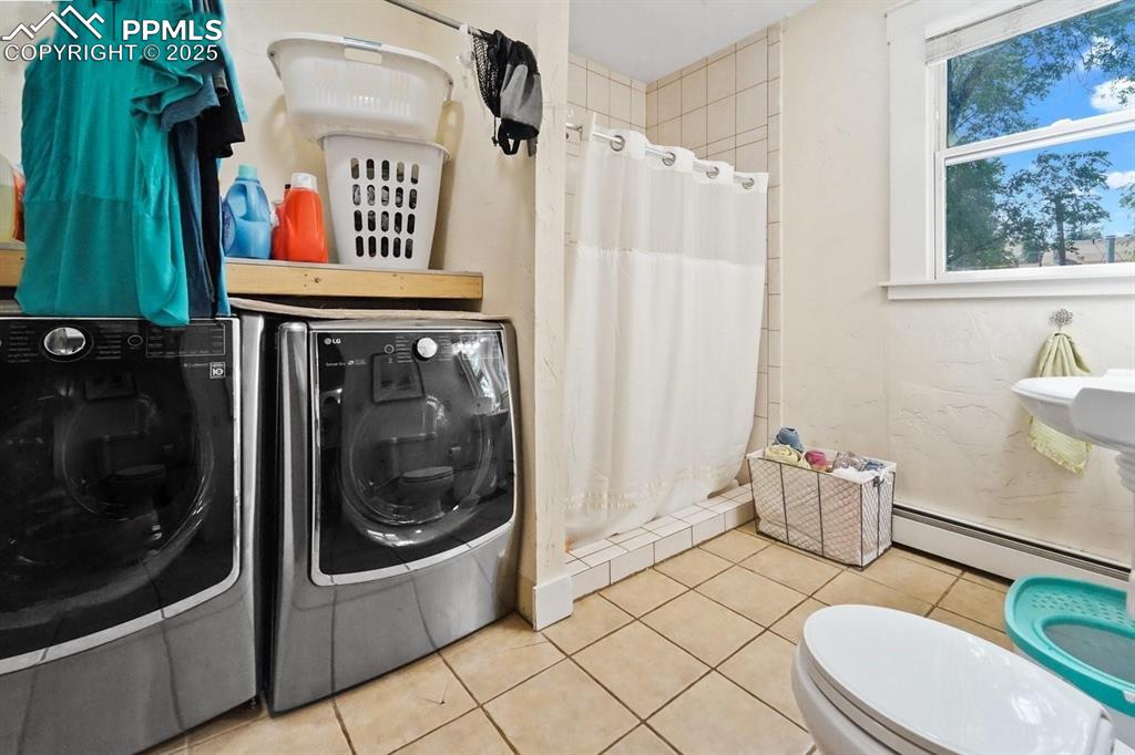 Image 13 of 28: Bathroom featuring baseboard heating, a stall shower, tile patterned floori