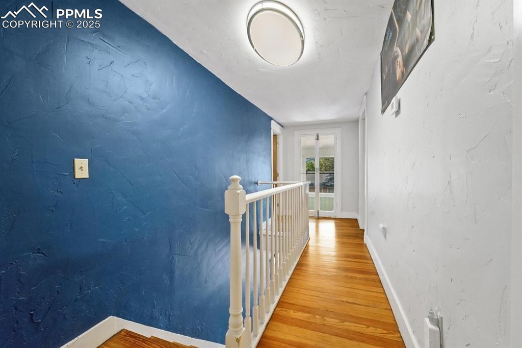 Image 14 of 28: Hallway featuring a textured wall, an upstairs landing, and light wood fini