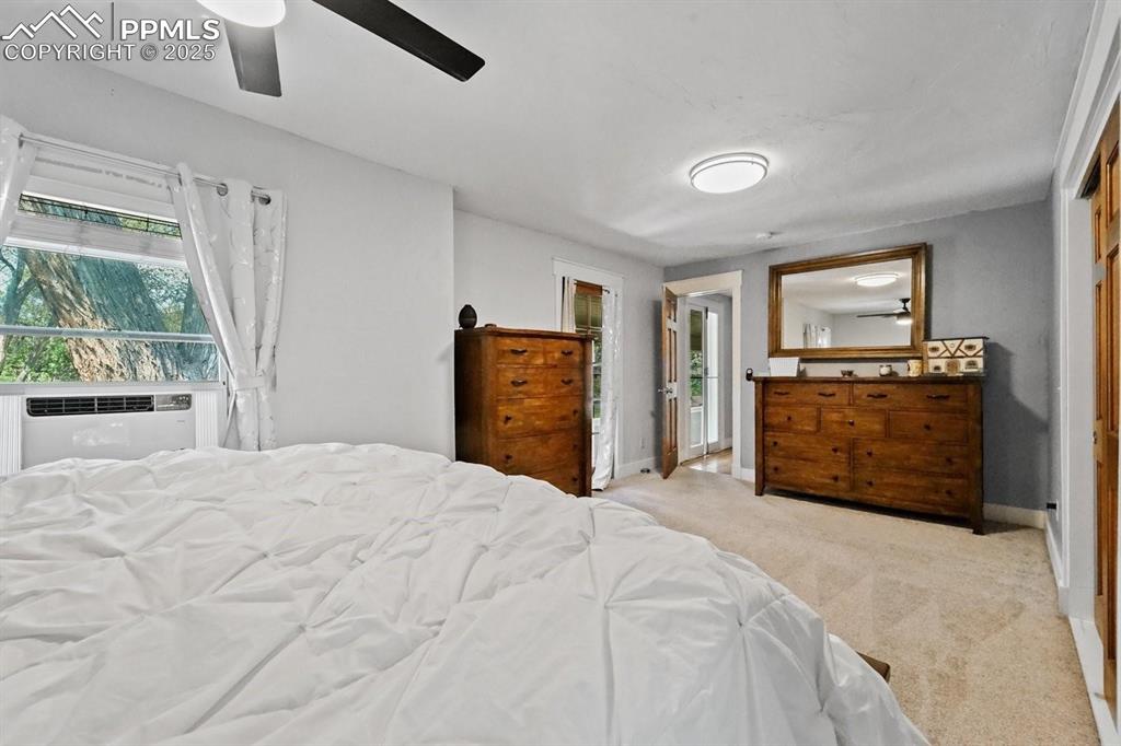 Image 16 of 28: Bedroom with light colored carpet, multiple windows, and ceiling fan