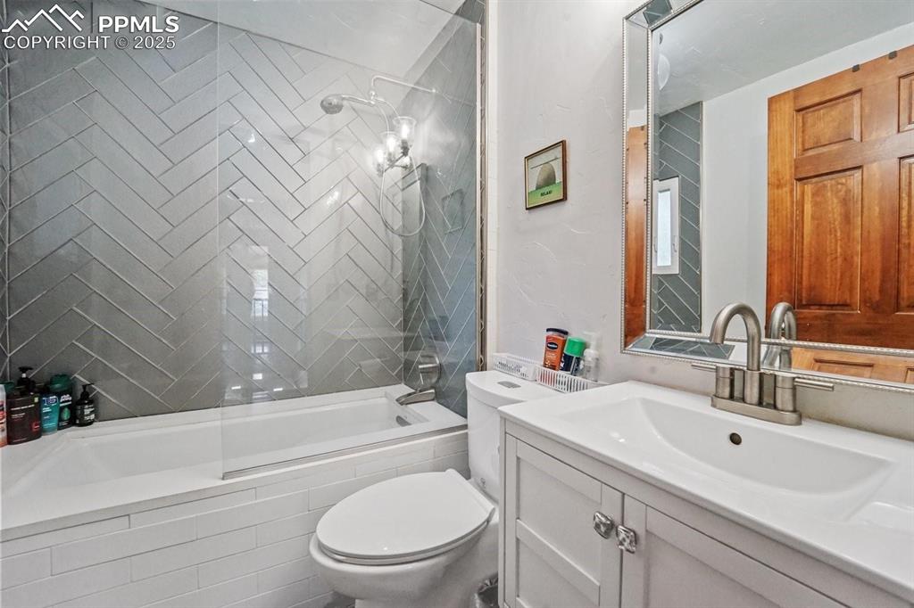 Image 22 of 28: Bathroom with tiled shower / bath and vanity