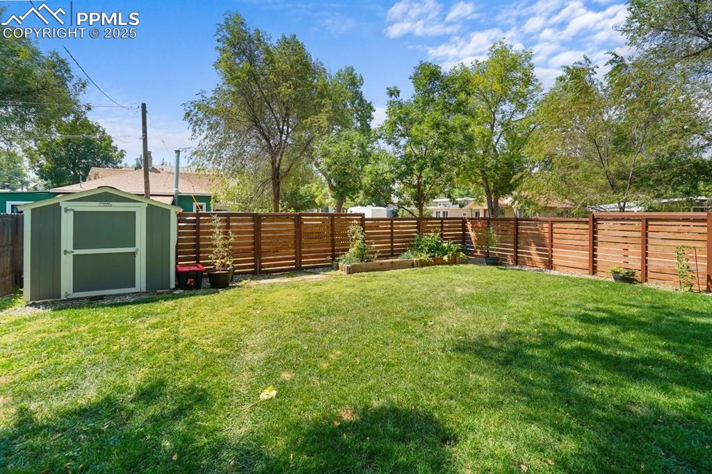 Image 26 of 28: Fenced backyard featuring a storage unit