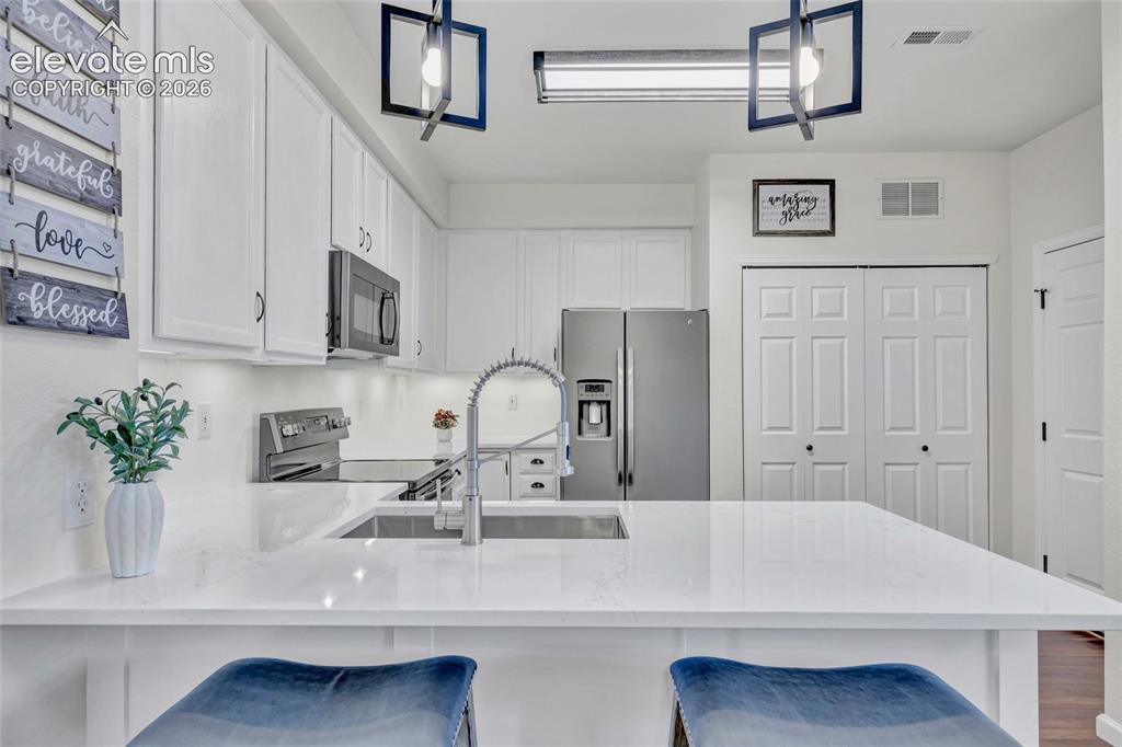 Image 10 of 26: The kitchen dazzles with crisp white cabinetry, gleaming quartz countertops