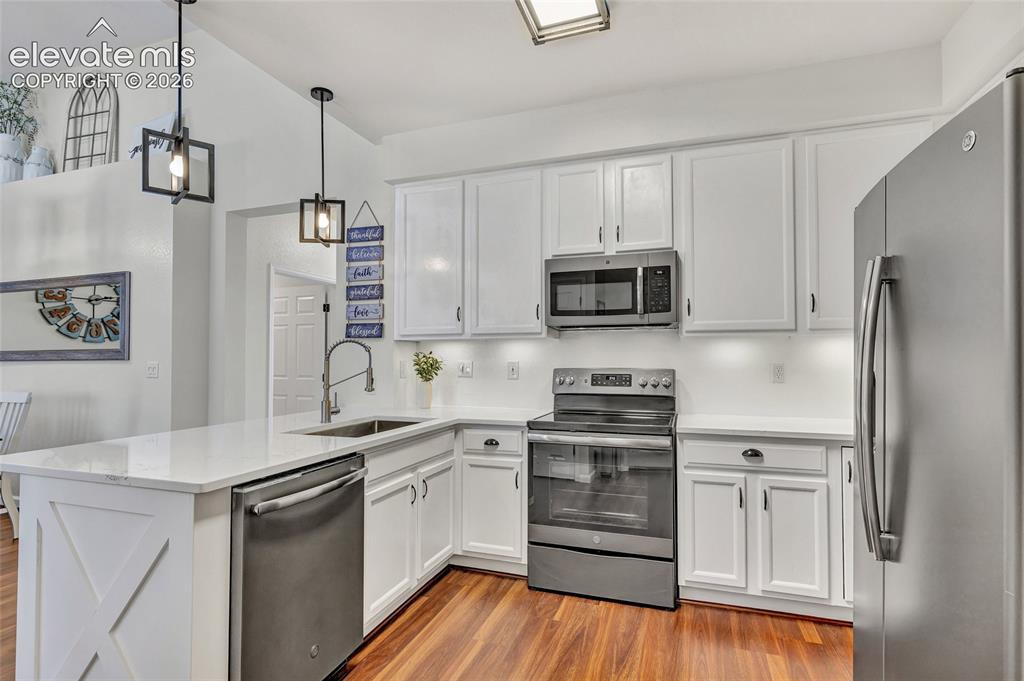 Image 14 of 26: A full view of the kitchen showcases abundant white cabinetry, a full suite