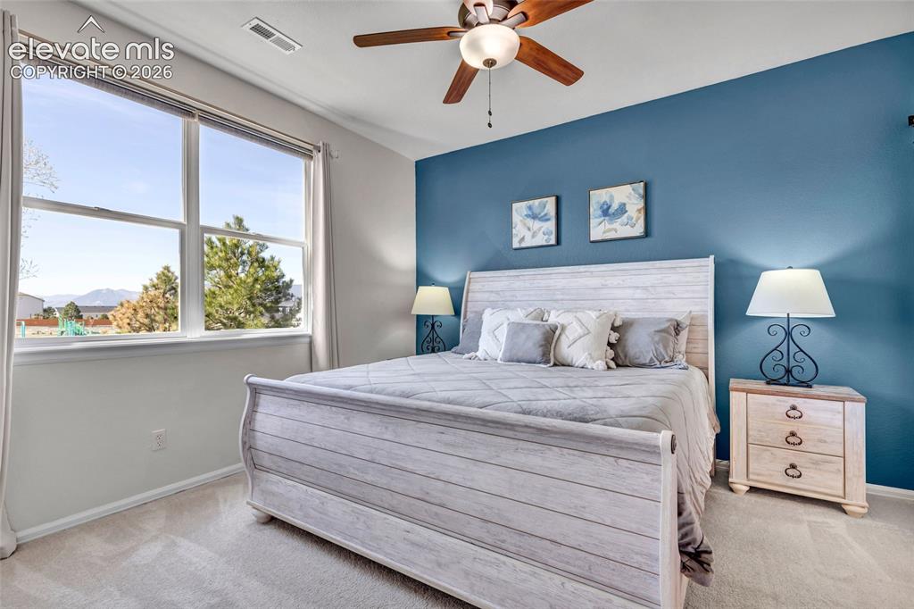 Image 15 of 26: The spacious primary bedroom captivates with a bold blue accent wall, a whi