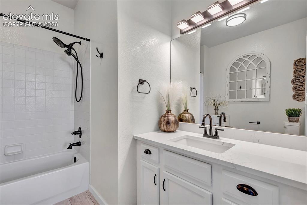 Image 16 of 26: The primary en-suite bath features a tub/shower combo with black fixtures,