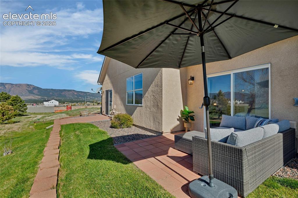 Image 21 of 26: Step outside to a private patio oasis where a wicker sectional, shaded umbr