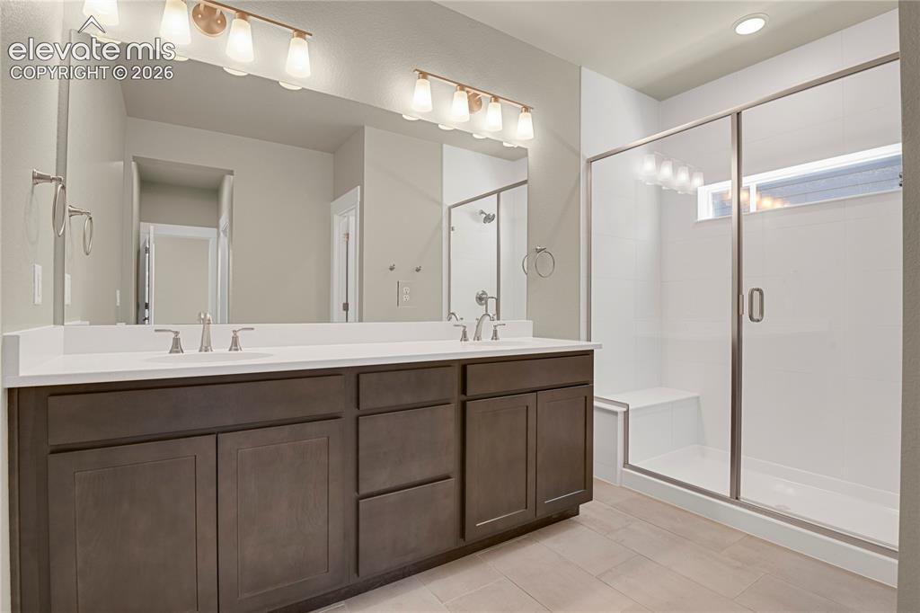 Image 15 of 42: Primary bath with dual sinks, quartz counter, fully tiled shower with bench